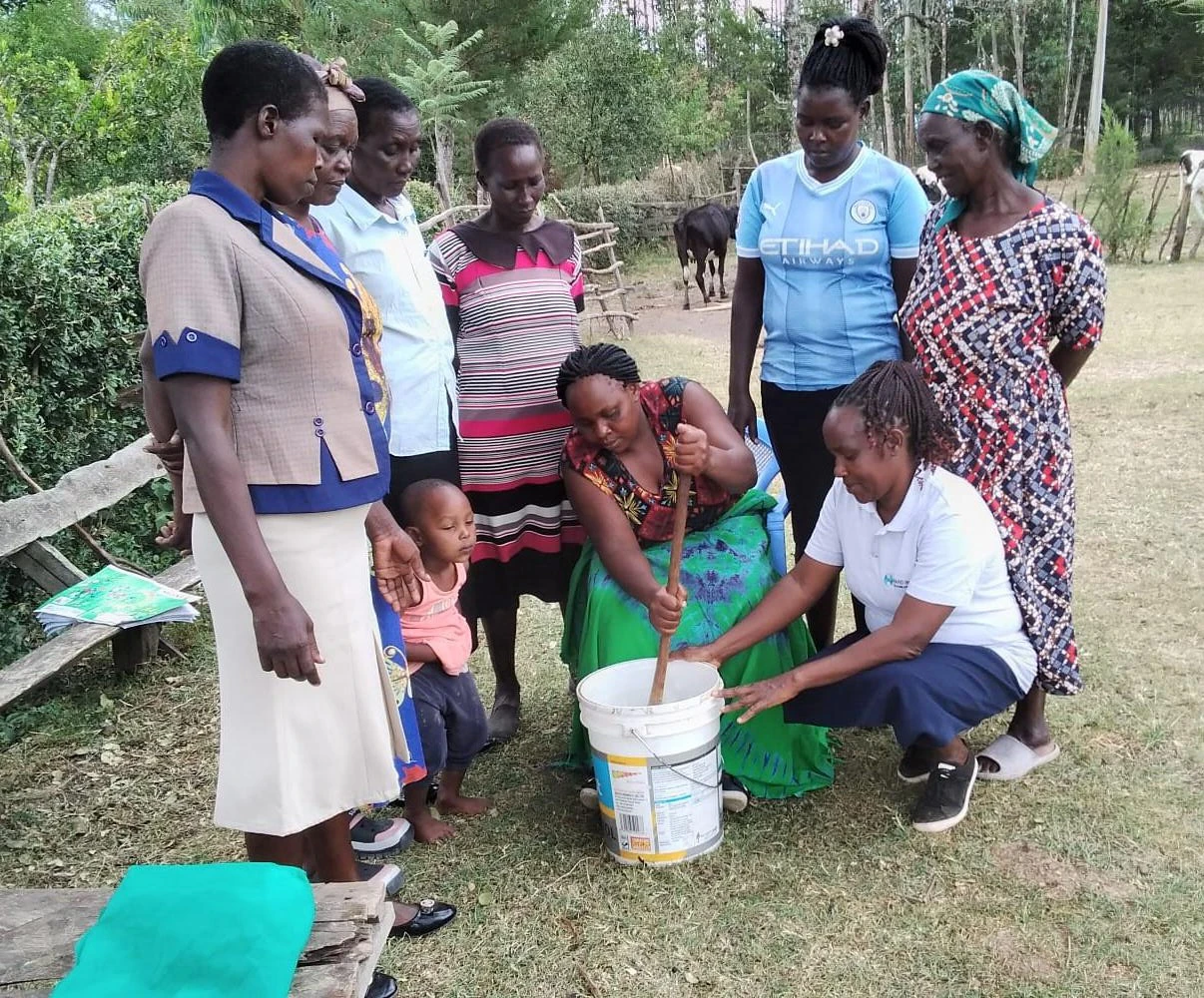 Margaret (in white polo t-shirt) business trainer showing members how to make liquid soap.